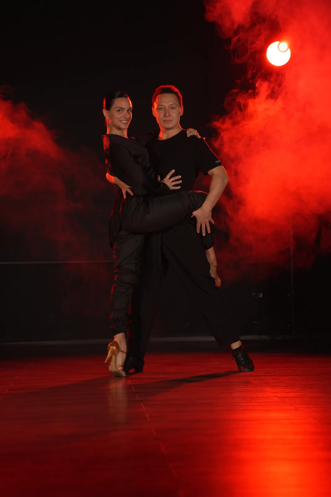 Пара танцует латину в красном свете в зале ORO Dance Studio